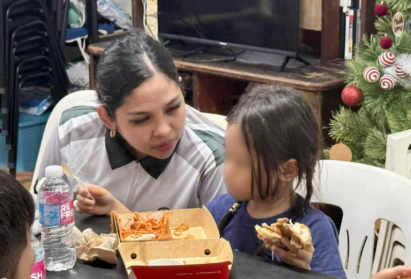A Bednbody team member eating with a child at a holiday gathering